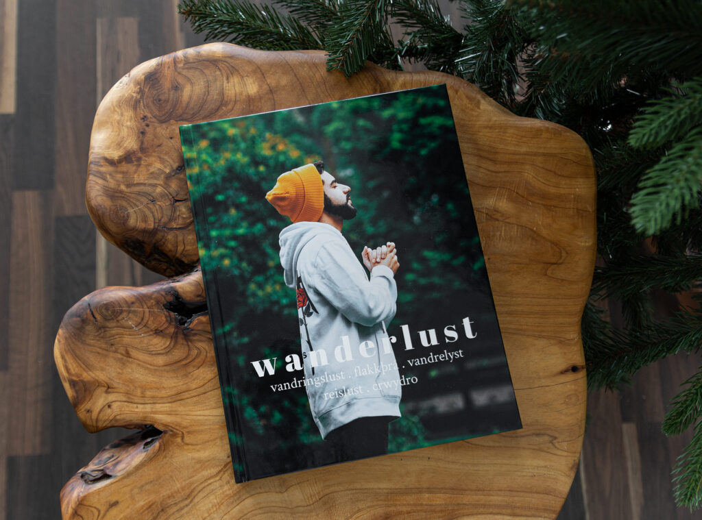 Hardcover Fotobuch mit "Wanderlust"-Cover liegt auf dem Tisch